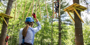 Young adults in safety harnesses walking a rope bridge on a challenge course designed and built by ABEE Inc. in Wisconsin Dells.